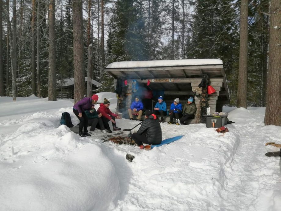 Lunch break around an open fire in the wintry forest.